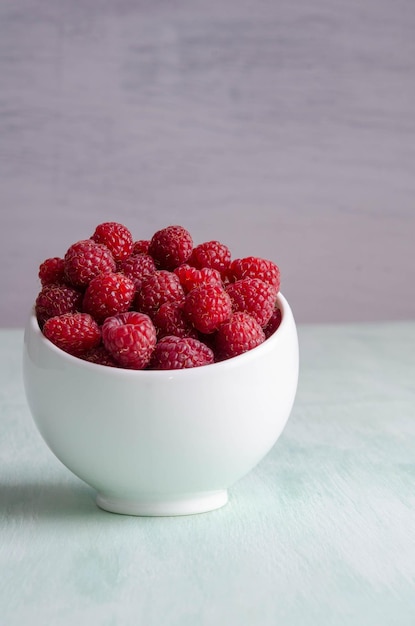 Rijpe frambozen in witte kom op de tafel