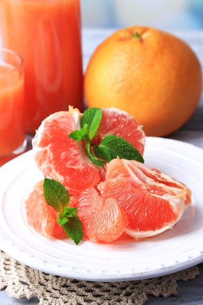 Rijpe gepelde grapefruits op plaat op houten kleurentafel op lichte achtergrond