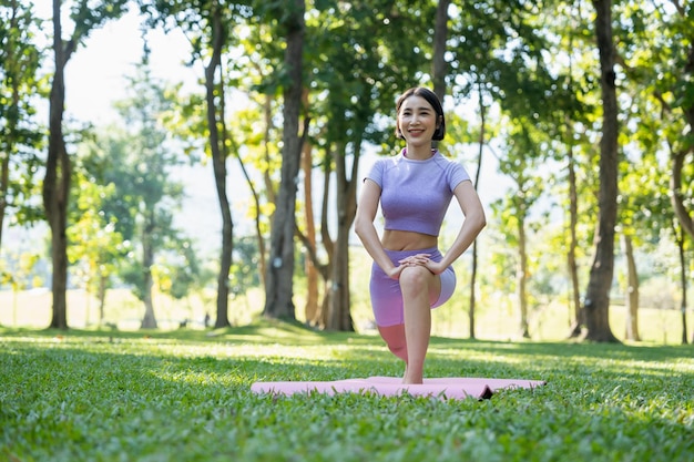 Rijpe gezonde mensen die yoga doen bij park Aziatische vrouw die op groen gras met yogamat uitoefent