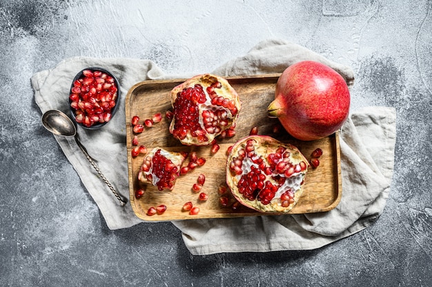 Rijpe granaatappel en zaden in een houten kom. Biologisch fruit. Grijze achtergrond. Bovenaanzicht