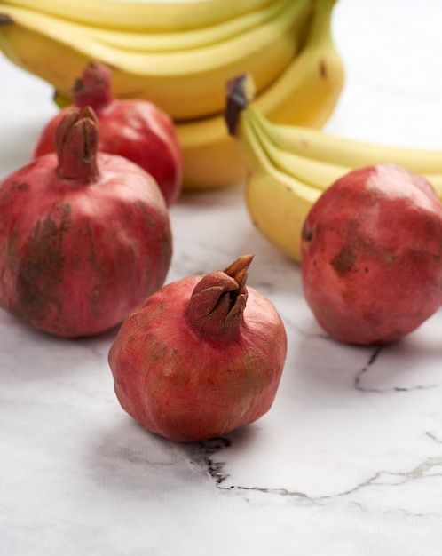 Rijpe granaatappels en bananen op marmeren tafel