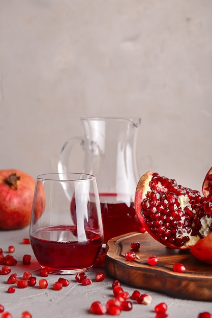 Foto rijpe granaatappels en glaswerk met sap op tafel