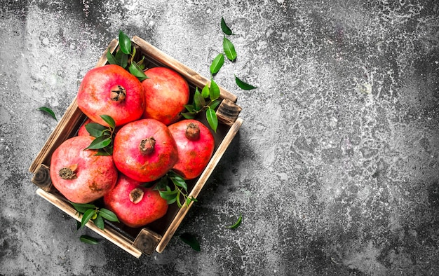 Rijpe granaatappels in een doos. Op een rustieke tafel.