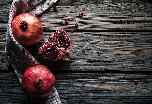 Rijpe granaatappels, servet en tafelmes op witte houten achtergrond