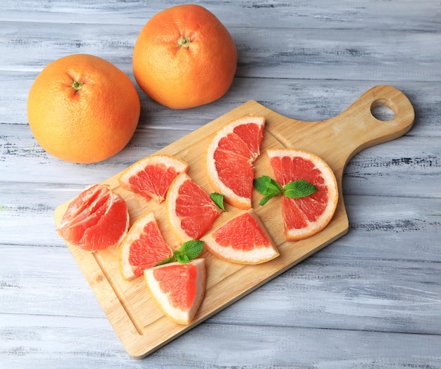 Rijpe grapefruits op snijplank op houten tafel op lichte achtergrond