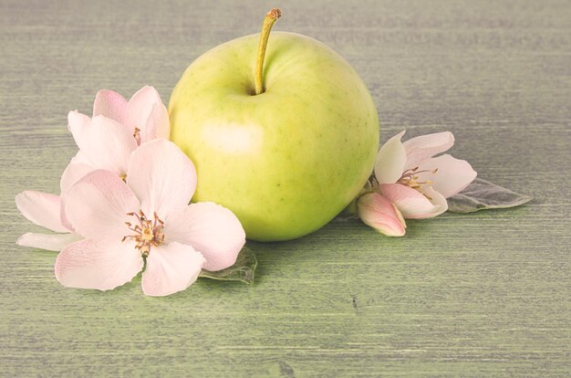 Rijpe groene appel fruit witte bloemen en verse bladeren op houten tafel achtergrond