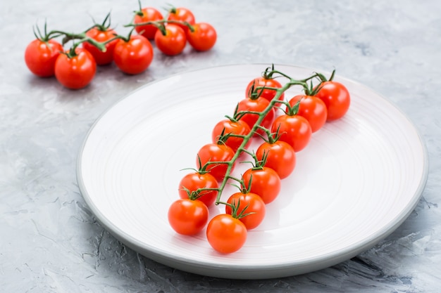 Rijpe honing cherrytomaatjes op een tak op een plaat