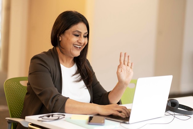 Rijpe Indiase vrouw met behulp van laptop communicatie online zwaaiende hand met video