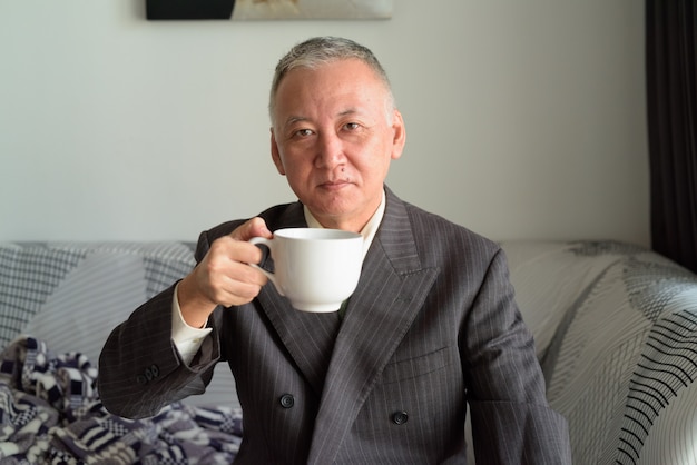 Rijpe Japanse zakenman het drinken koffie thuis