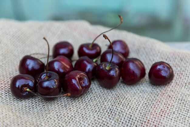 Rijpe kersen op jute op een blauwe houten achtergrond. Vitaminen uit de natuur. Detailopname.