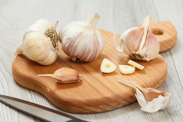 Rijpe knoflook op houten snijplank en roestvrijstalen mes met grijze achtergrond