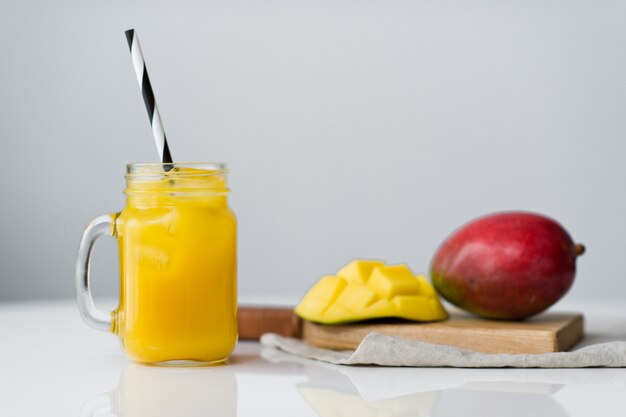 Rijpe mango en een glas mangosap op een houten snijplank.