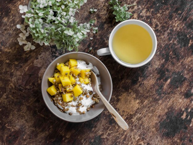 Rijpe mango muesli Griekse yoghurt en groene thee heerlijke ontbijtbrunch op een houten achtergrond bovenaanzicht