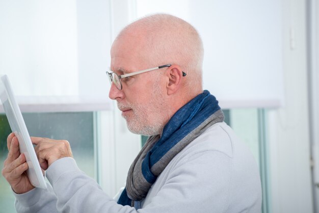 Rijpe mens die digitale tablet thuis gebruikt