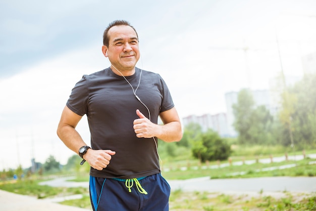 Rijpe mens die jogging op een stadsstraat doet. Senior man leidt een gezonde en actieve levensstijl sporten.