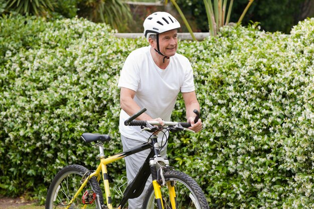 Rijpe mens die met zijn bergfiets loopt