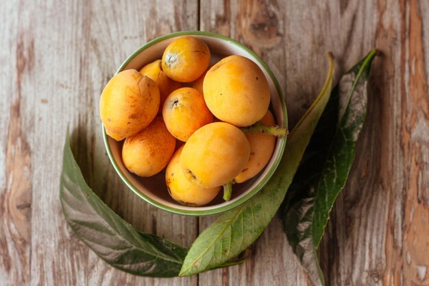 Foto rijpe mispel fruit eriobotrya japonica en groene mispel bladeren op houten tafel top view