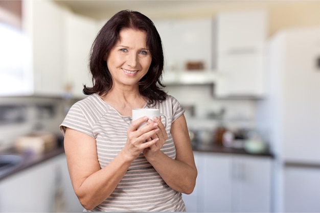 Rijpe mooie vrouw met cup op background