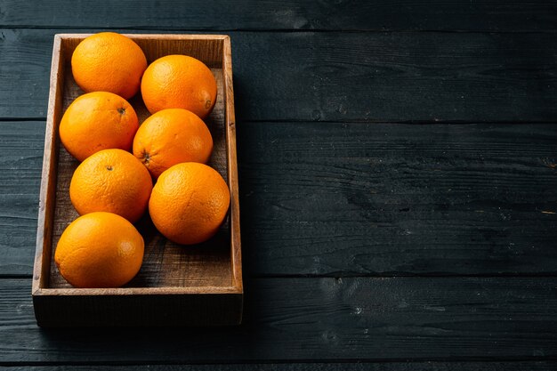 Rijpe oranje fruitset, in houten kist, op zwarte houten tafel