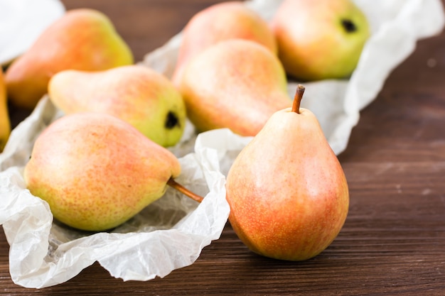 Rijpe peren in een papier op een houten tafel