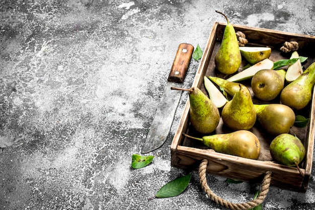 Rijpe peren op een dienblad met een oud mes. Op een rustieke achtergrond.