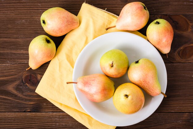 Rijpe peren op een plaat op een houten tafel, bovenaanzicht