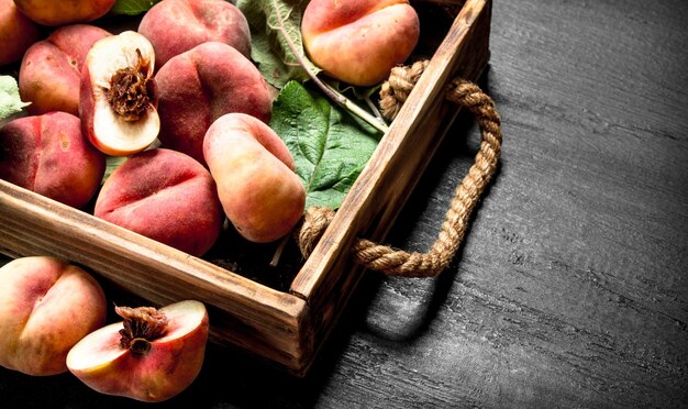 Rijpe perziken in een houten kist op het zwarte bord