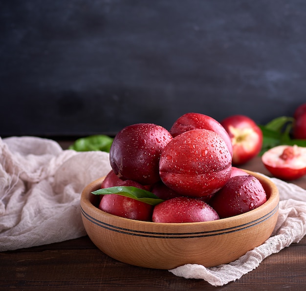 Rijpe perziken nectarine in een bruine houten kom