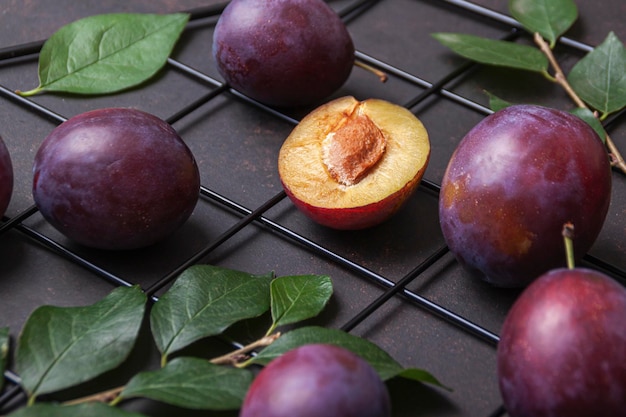 Rijpe pruimen met bladeren op tafel. Zomer fruit achtergrond. Bovenkant pruim, plat gelegd