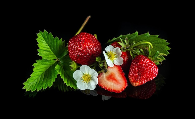 Rijpe rode aardbeien met bladeren en bloemen op een zwarte achtergrond