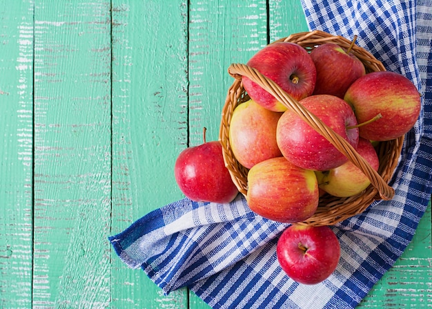 Rijpe rode appels in een mand op een lichte houten achtergrond.