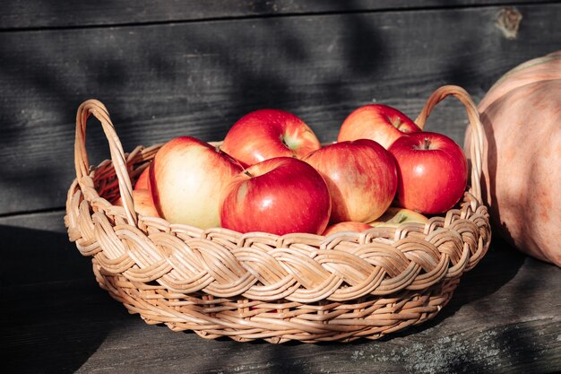 Rijpe rode appels in een rieten mand op een houten ondergrond