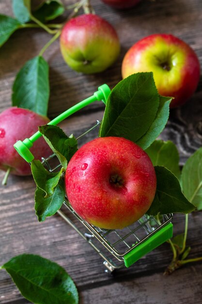 Rijpe rode appels in winkelwagen op houten achtergrond