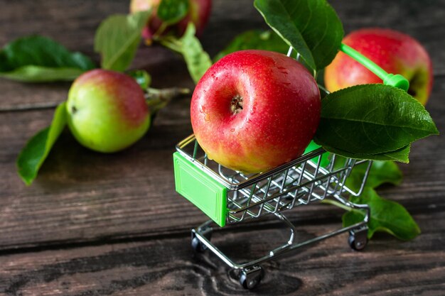 Rijpe rode appels in winkelwagen op houten achtergrond