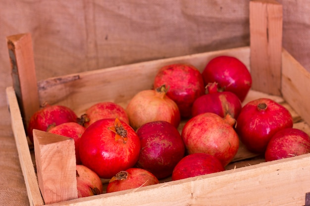 Rijpe rode granaatappels in een houten doos op bruine jute