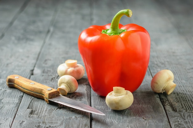 Rijpe rode paprika met champignons op een houten tafel. Vegetarisch eten.