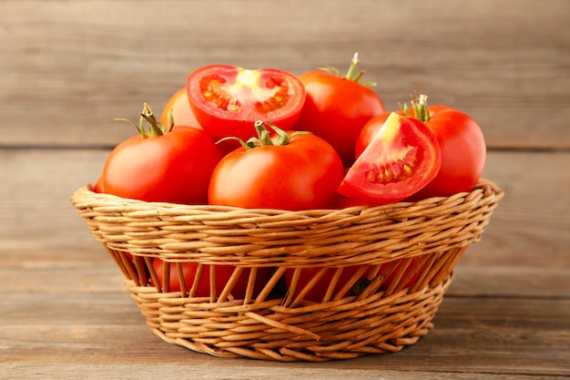 Rijpe rode tomaten in mand op grijs