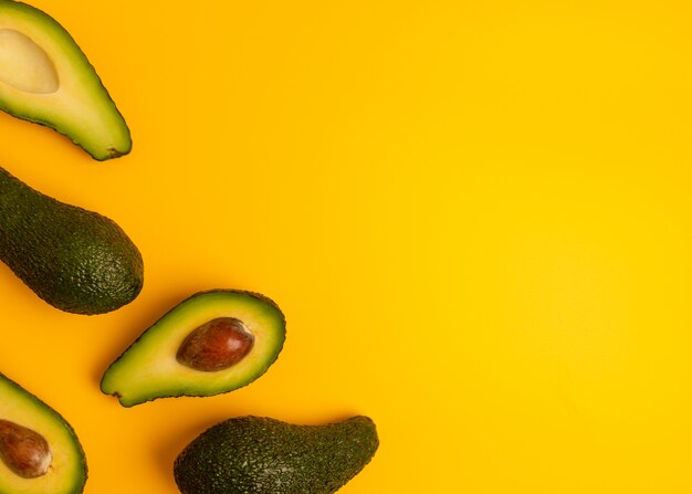 Rijpe sappige gehalveerde avocado op een gele stevige achtergrond met kopie ruimte. Veganistisch, vegetarisch, rauw biologisch voedsel sjabloon. Eco detox-stijl.