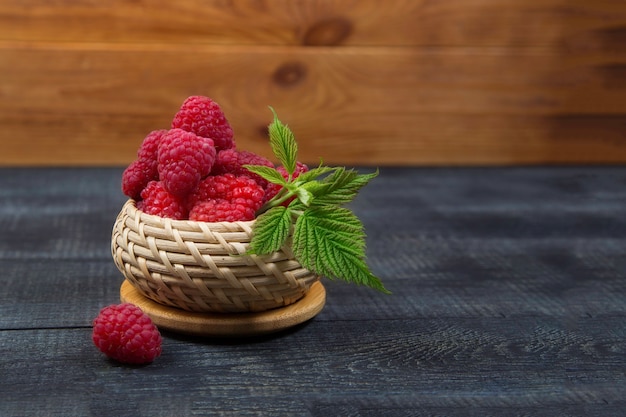 Rijpe smakelijke heldere Verse frambozen in een rieten mand op een snijplank op een houten achtergrond