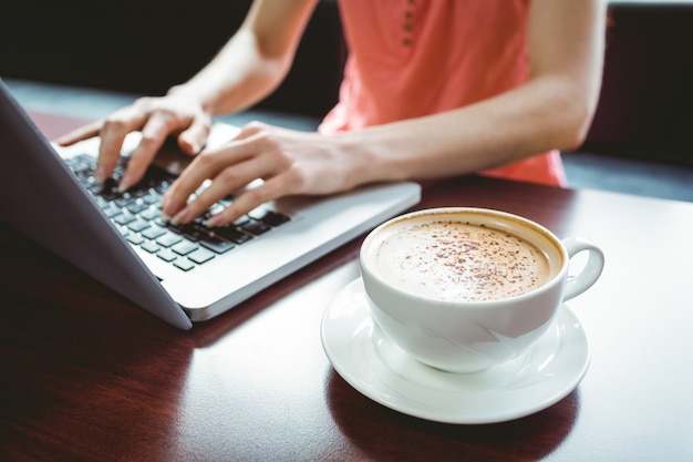 Rijpe student die laptop in koffie met behulp van