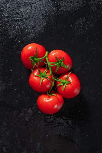 Rijpe tomaten op donkere stenen tafel. Bovenaanzicht. Plat leggen