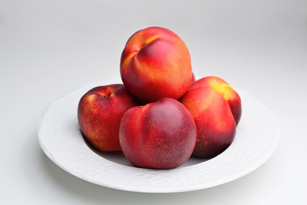 Rijpe verse nectarine op een witte keramische plaat een mooie geurige rijpe nectarine