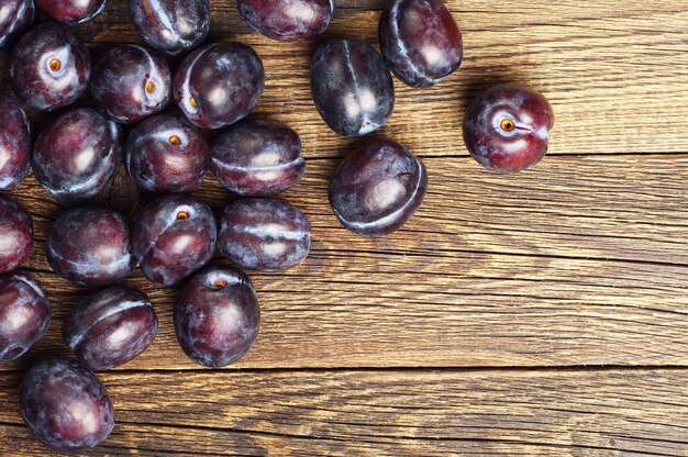 Rijpe violette pruimen op houten achtergrond