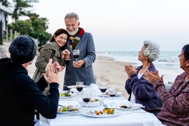 Rijpe vrienden die een diner bij het strand hebben