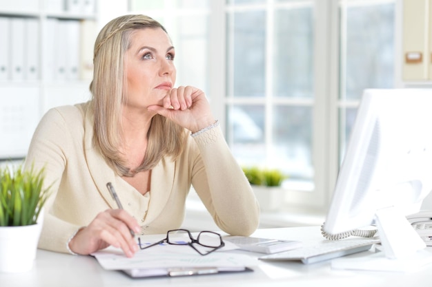 Rijpe vrouw die computer gebruikt