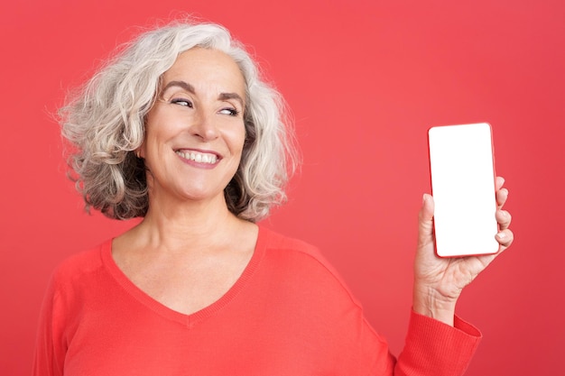 Rijpe vrouw die het lege scherm van mobiel toont