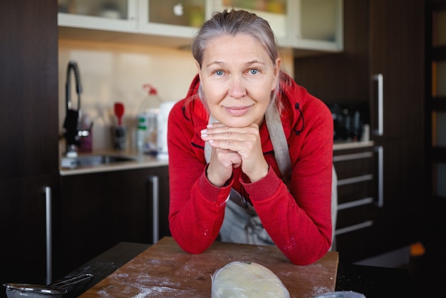 Rijpe vrouw die in keuken voedsel voorbereidt