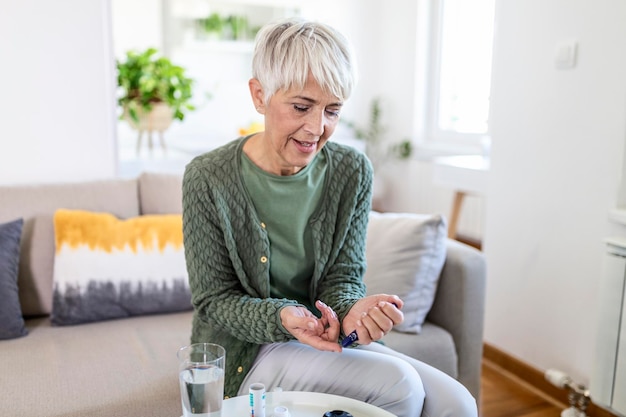 Rijpe vrouw die met glucometer bloedsuikerspiegel thuis controleert. Diabetes, zorgconcept