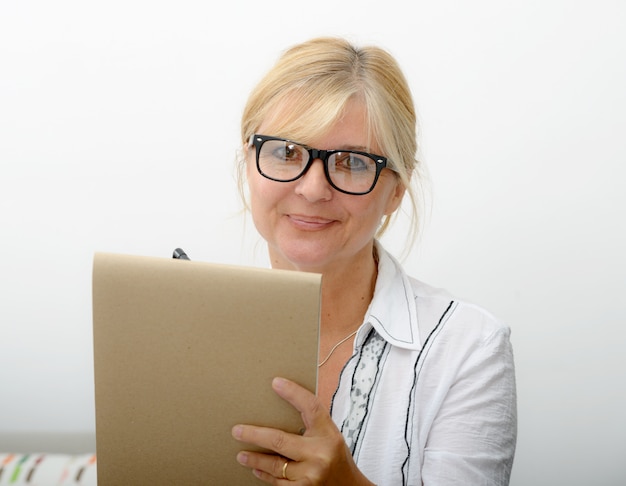 Rijpe vrouw die op een notitieboekje schrijft