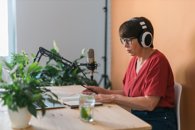 Rijpe vrouw die podcast-opname maakt voor haar online show Aantrekkelijke zakenvrouw die een koptelefoon gebruikt